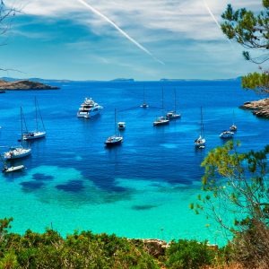 Sailboat and a yacht at Cala Salada turquoise lagoon cove